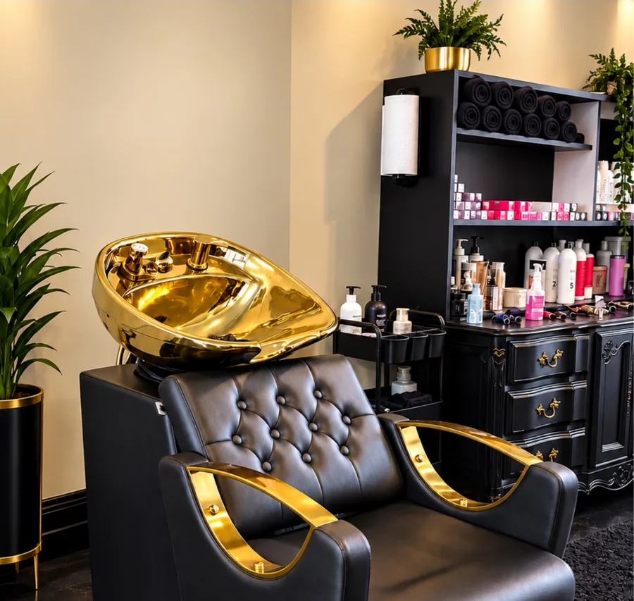Black salon chair and gleaming gold shampoo basin at Vogue Studio LLC