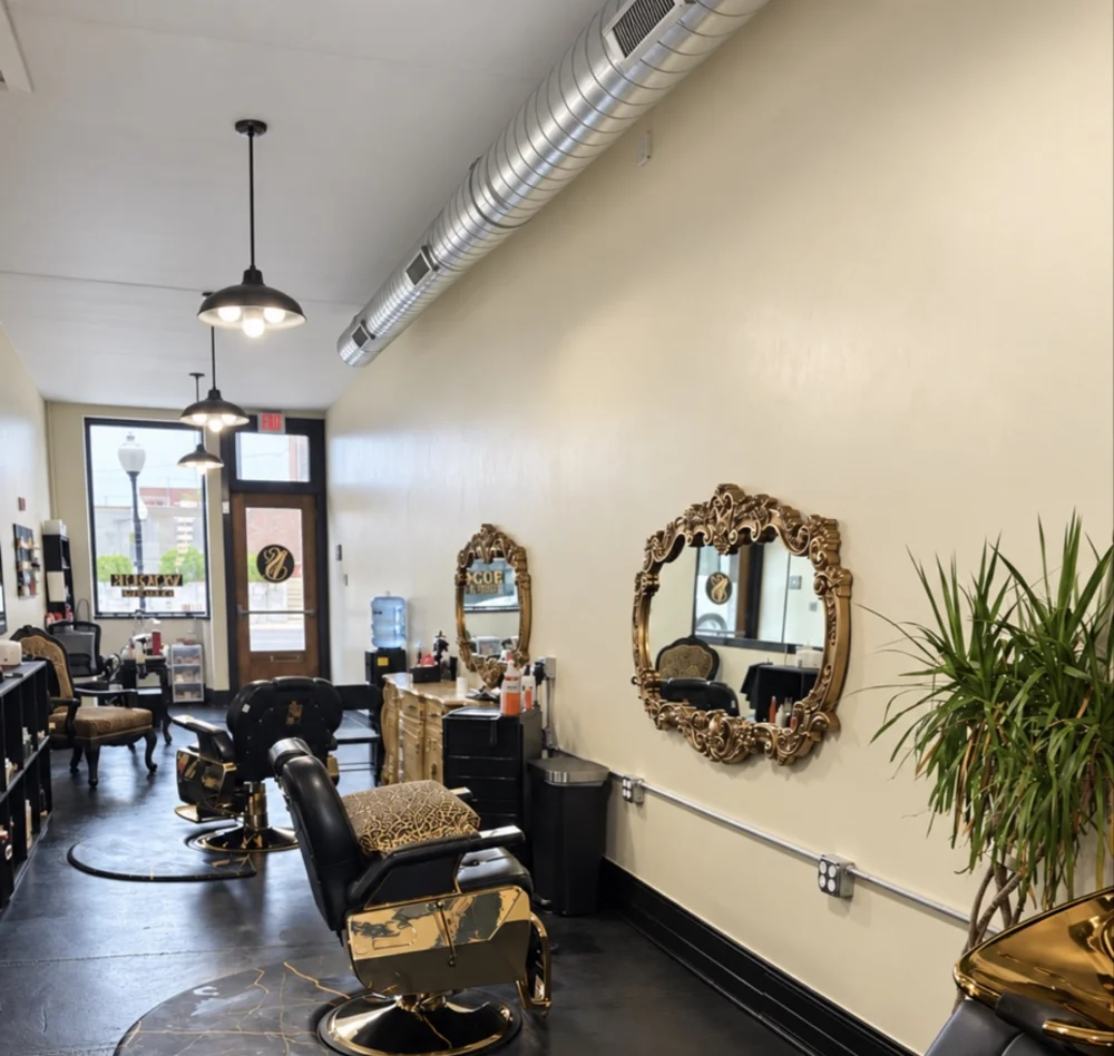 Inside Vogue Studio LLC: styling chairs, ornate gold mirrors, and warm cream walls